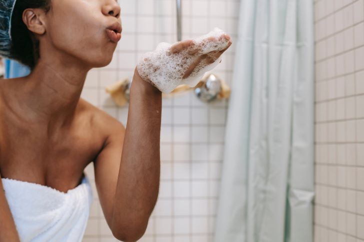 Vrouw Blaast Shampoo uit Haar Hand in de Badkamer
